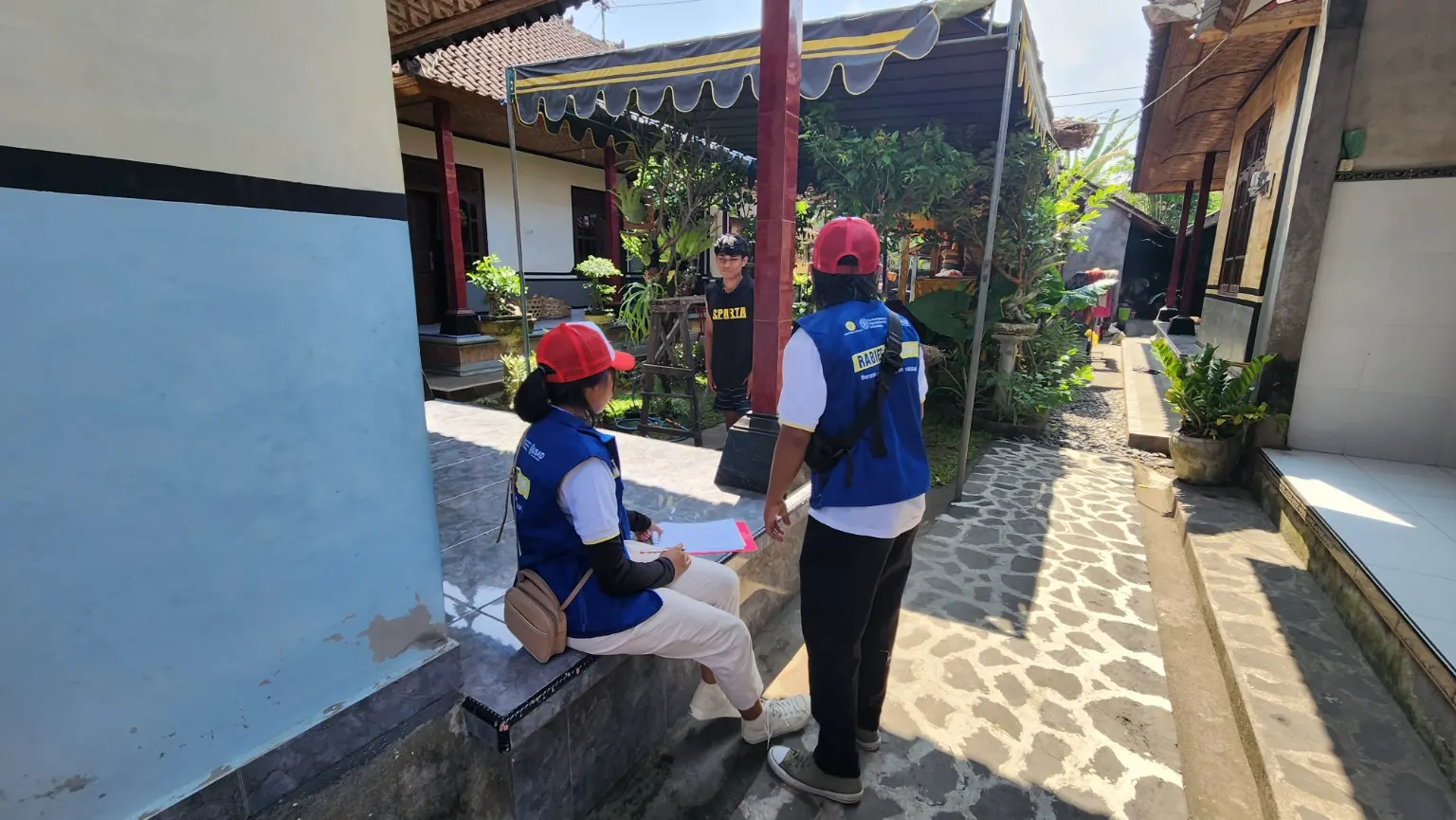 Dua petugas berdiskusi di halaman permukiman